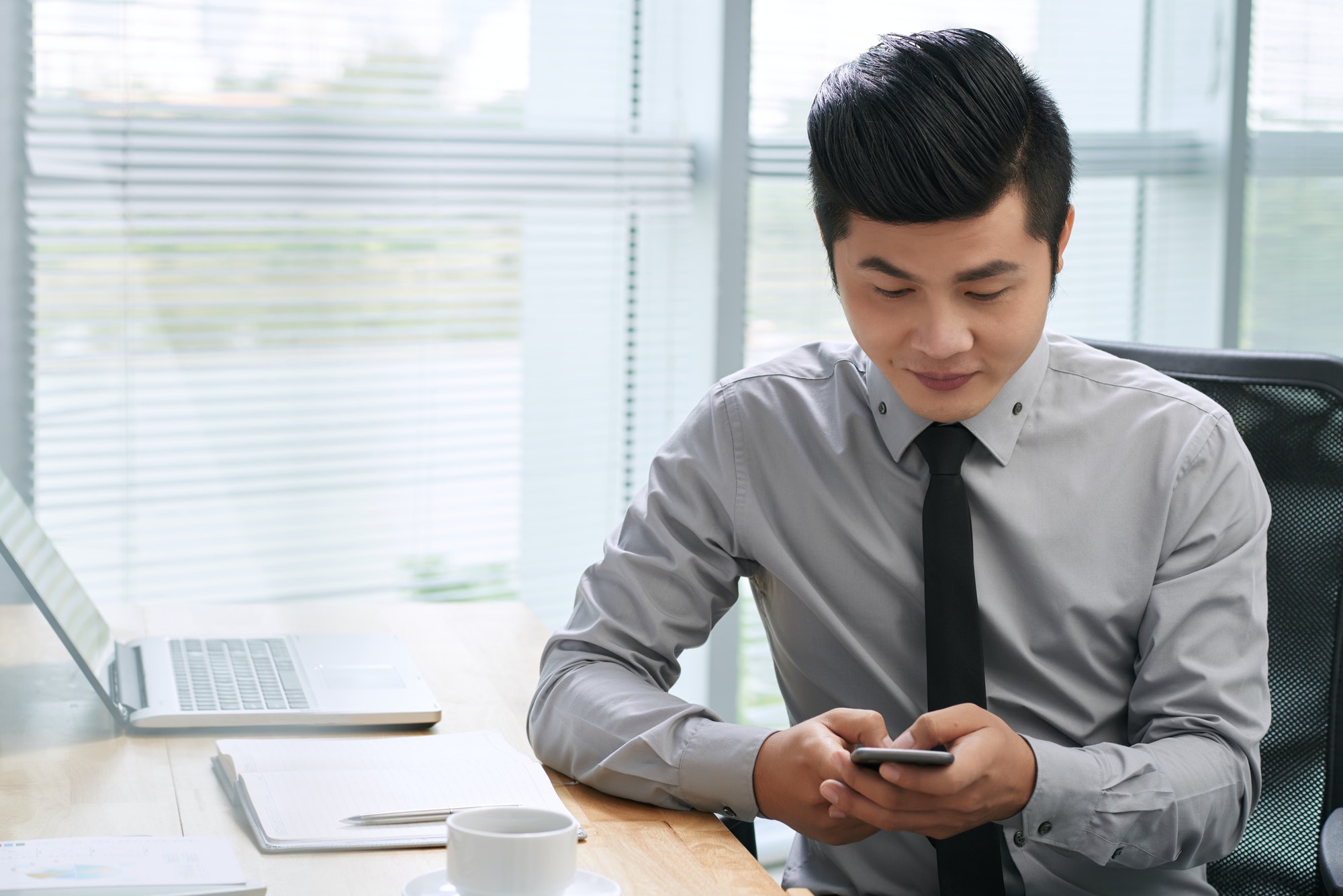 Asian businessman texting on smartphone